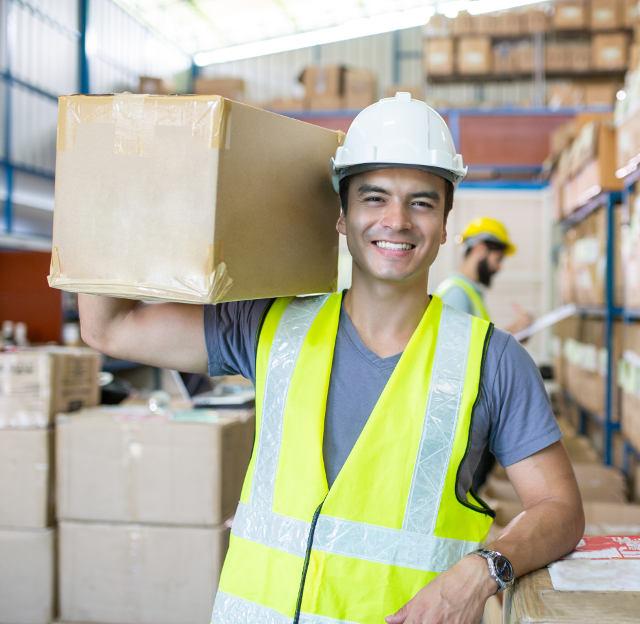 Man working for a staffing agency carrying a box in warehouse
