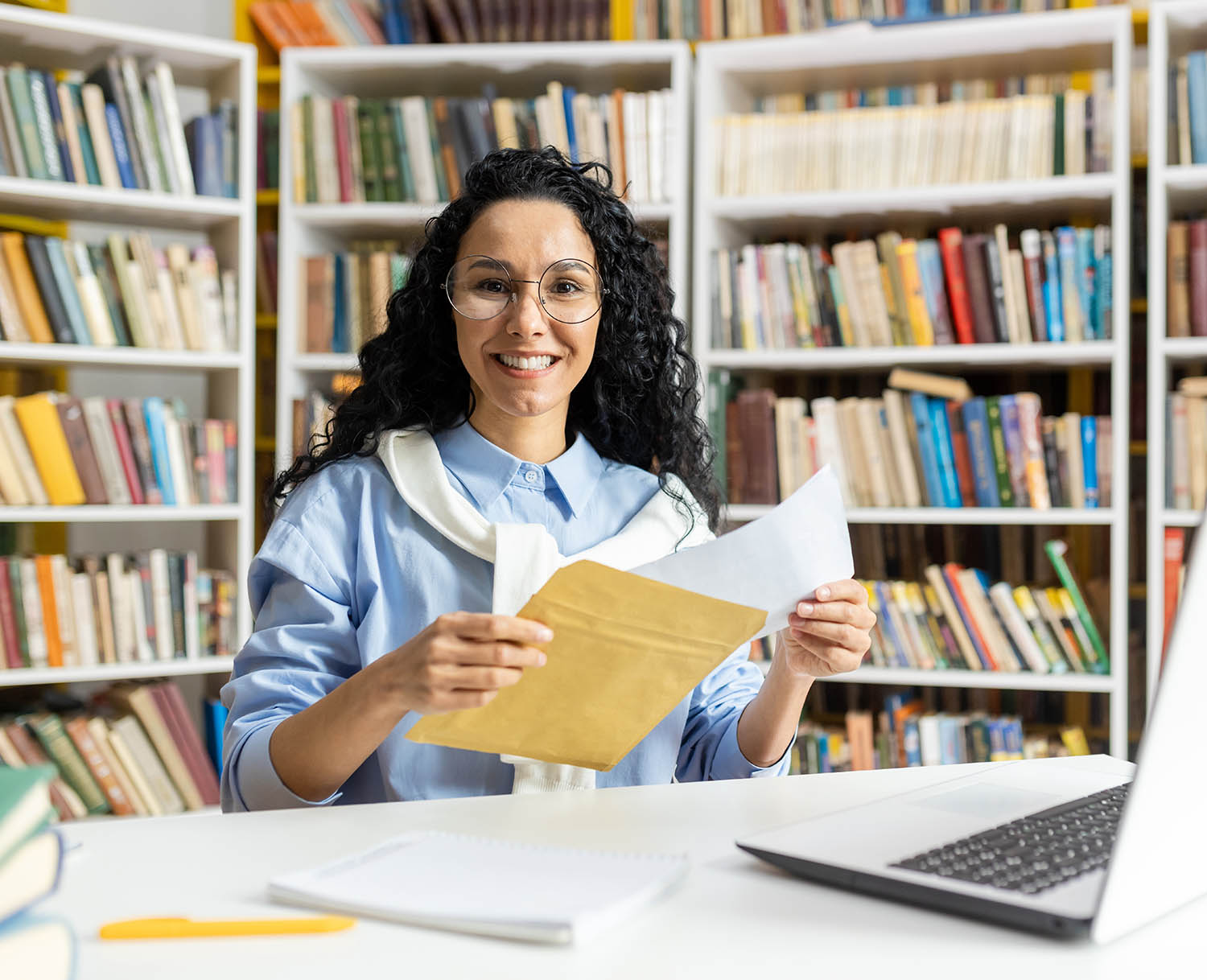 A happy female manages paperwork and digital entries on her laptop A happy female manages paperwork and digital entries on her laptop